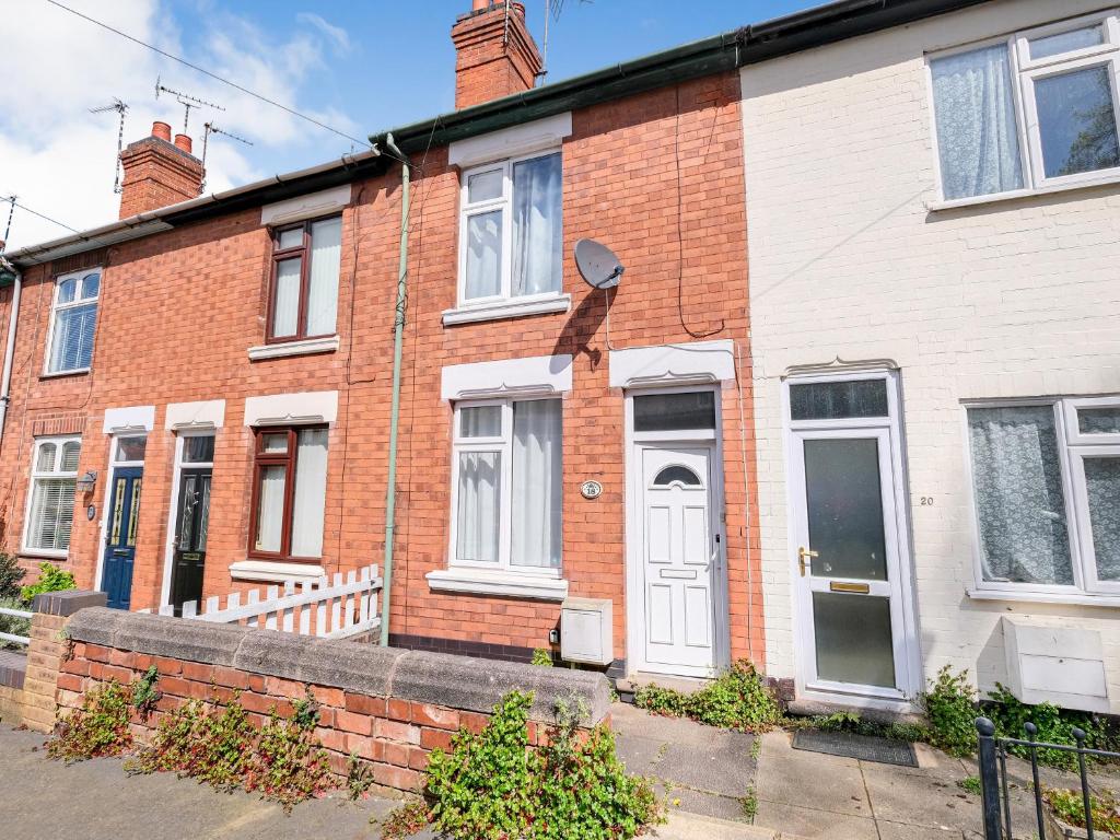 a red brick house with a white door at Lovely large 2-Bed House with 2 Reception Rooms in Atherstone