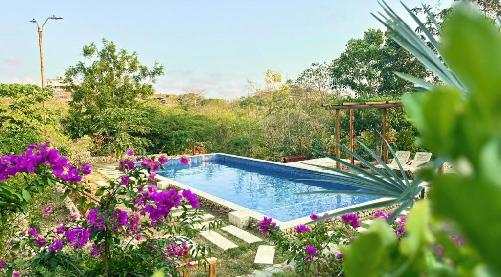 uma piscina num jardim com flores roxas em Ecohotel Summer Usiacuri em Usiacurí