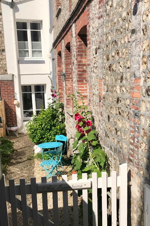 une clôture blanche devant un bâtiment en briques dans l'établissement Maison cosy vue mer à 50m de la plage, à Étretat
