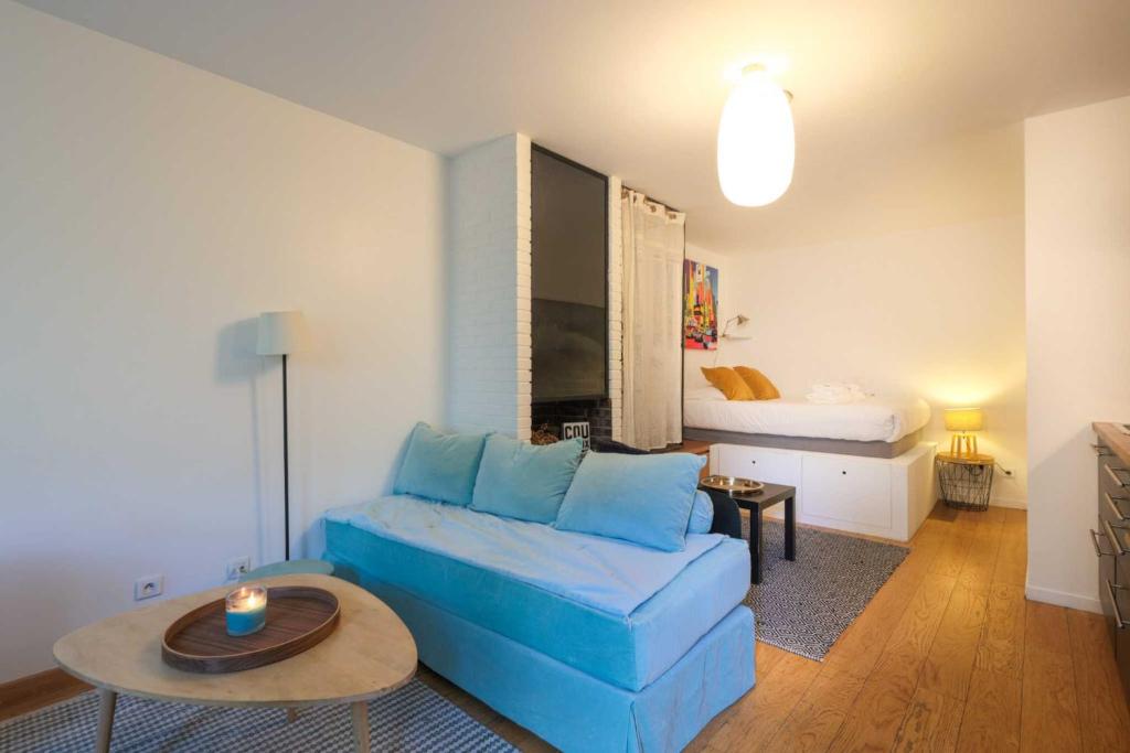 - un salon avec un canapé bleu et un lit dans l'établissement Charming studio apartment for 2 - Bastille, à Paris