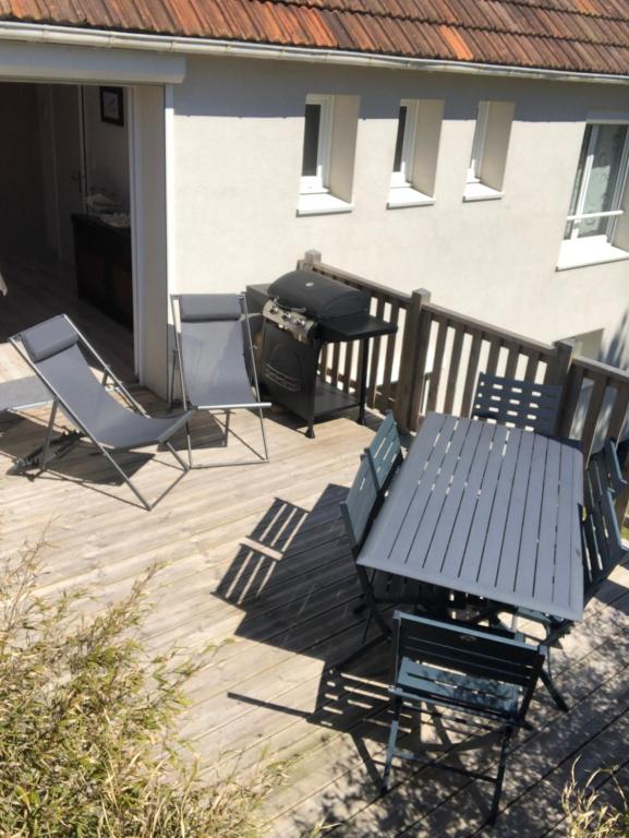 a picnic table and chairs on a patio with a grill at La Maison des phares in Lion-sur-Mer