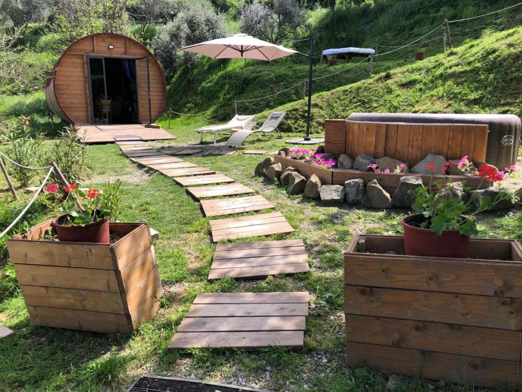 un jardín con escalones de madera, sofá y sombrilla en Le Botti Fiorentine, en Reggello