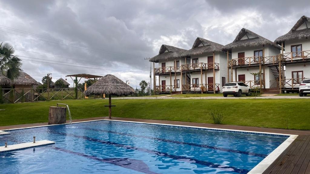 un complejo con piscina frente a un edificio en Sun Beach Chalés, en Luís Correia