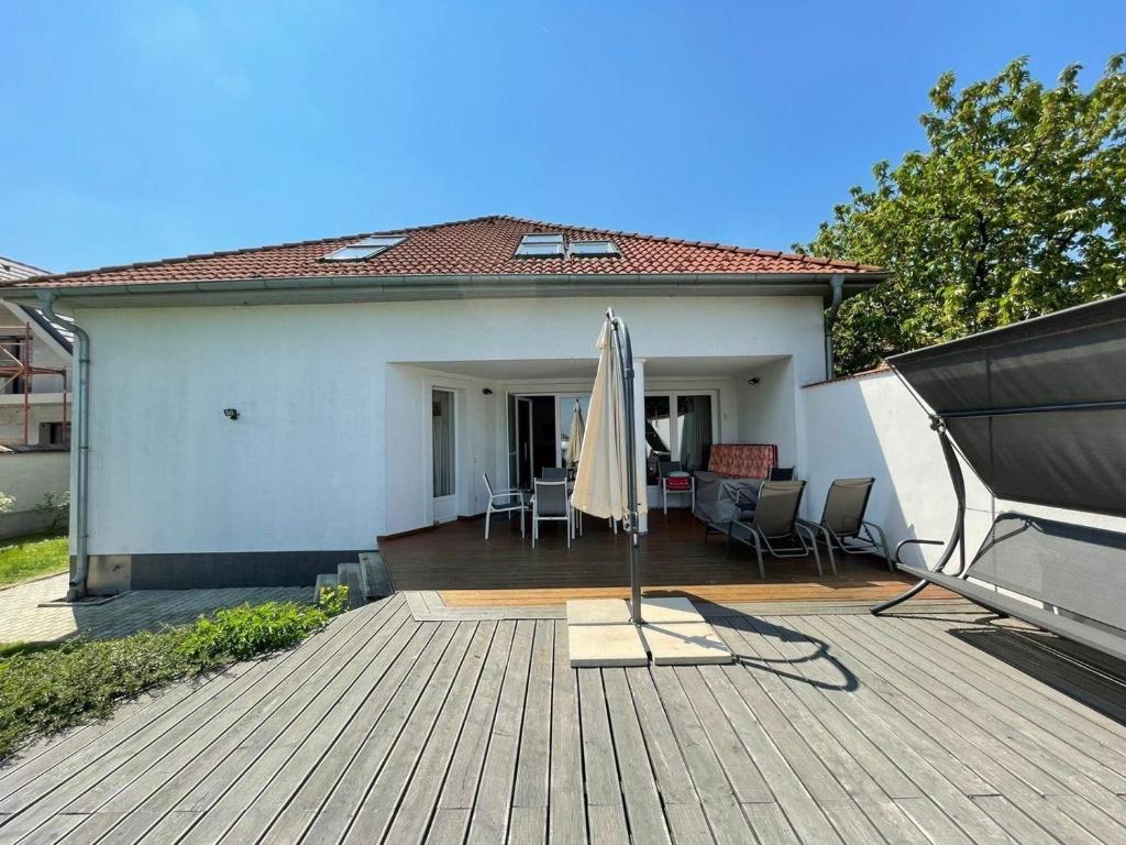 un patio con una sombrilla y una casa en Freistehendes Ferienhaus mit Swimmingpool, Kamin, Internet, unweit Neusiedlersee, en Fertőd