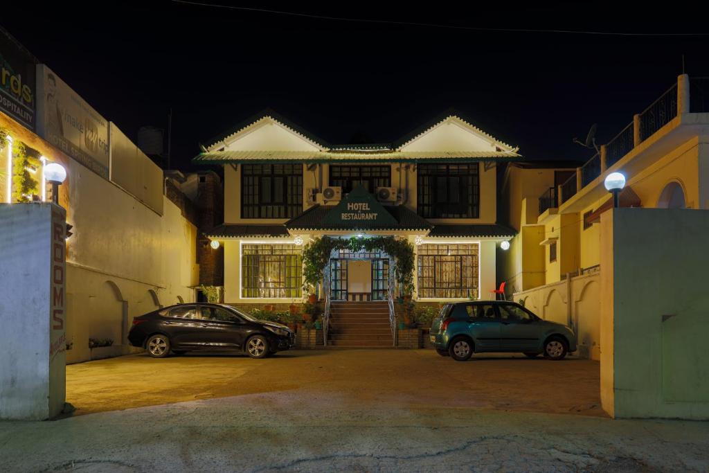 twee auto's geparkeerd voor een gebouw 's nachts bij Hotel Spring Birds in Bhīm Tāl
