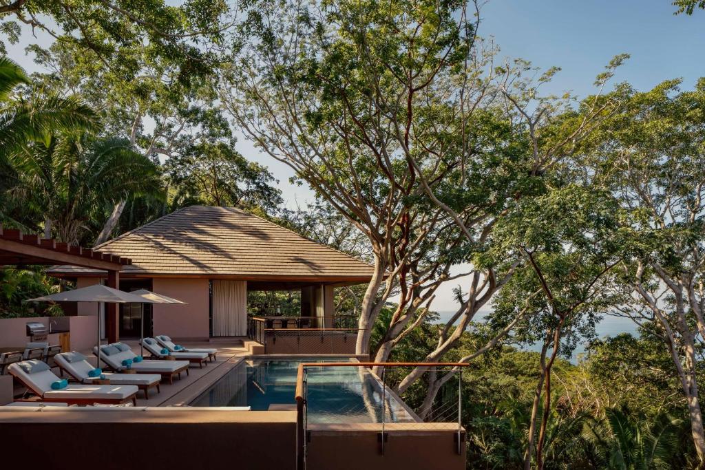 una casa y una piscina al aire libre con tumbonas en One&Only Mandarina en Lo de Marcos