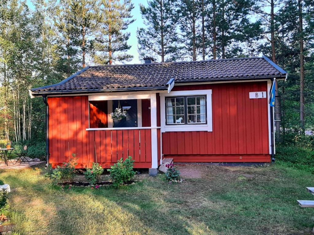 a red shed with a window in a yard at Kleines Ferienhaus auf Naturgrundstück in Seenähe - b48624 in Sollerön