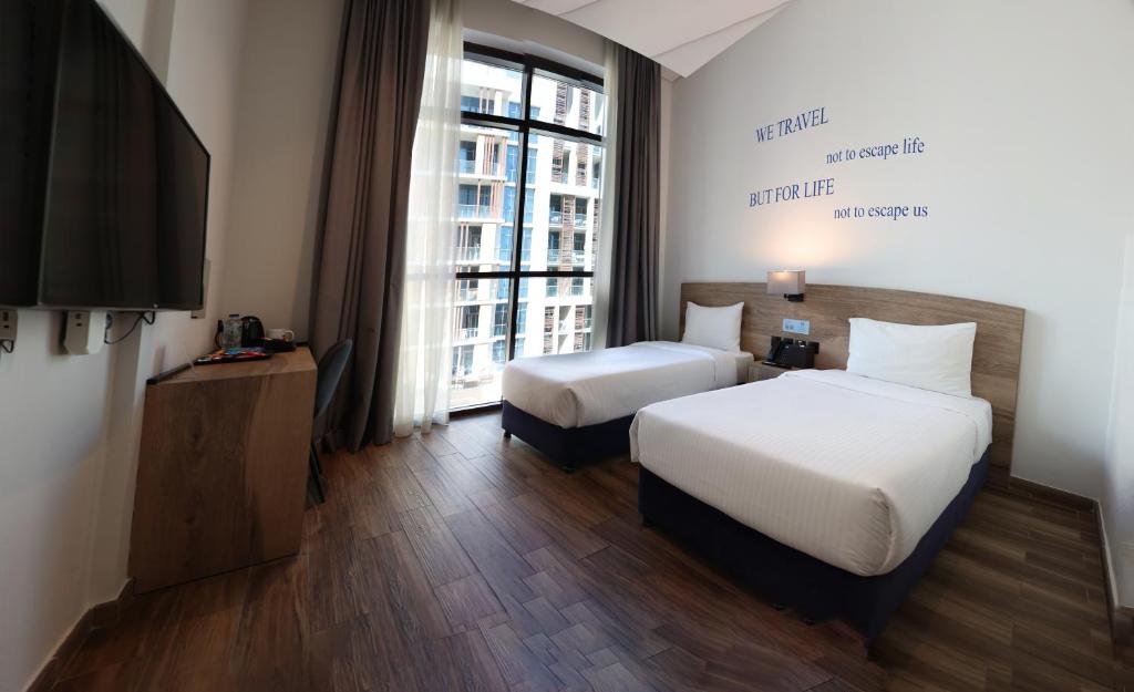 ein Hotelzimmer mit 2 Betten und einem TV in der Unterkunft Kingsgate Al Jaddaf Hotel by Millennium in Dubai