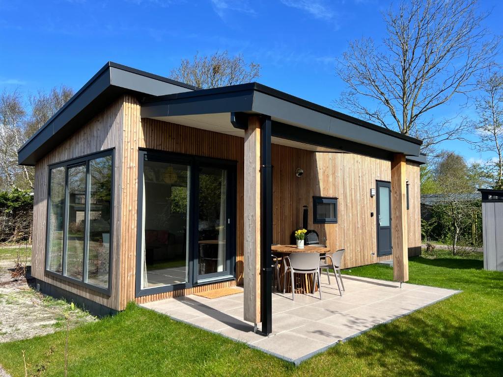un petit hangar avec une table dans l'herbe dans l'établissement Vakantiehuisje Zeegeluk vlakbij de kust, à Sint Maartenszee