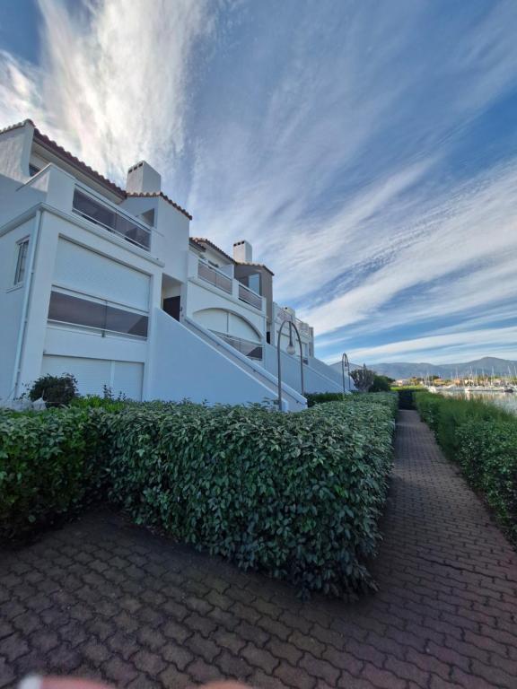 a white house with a hedge in front of it at Quai de la lagune - vue sur la Marina in Saint-Cyprien