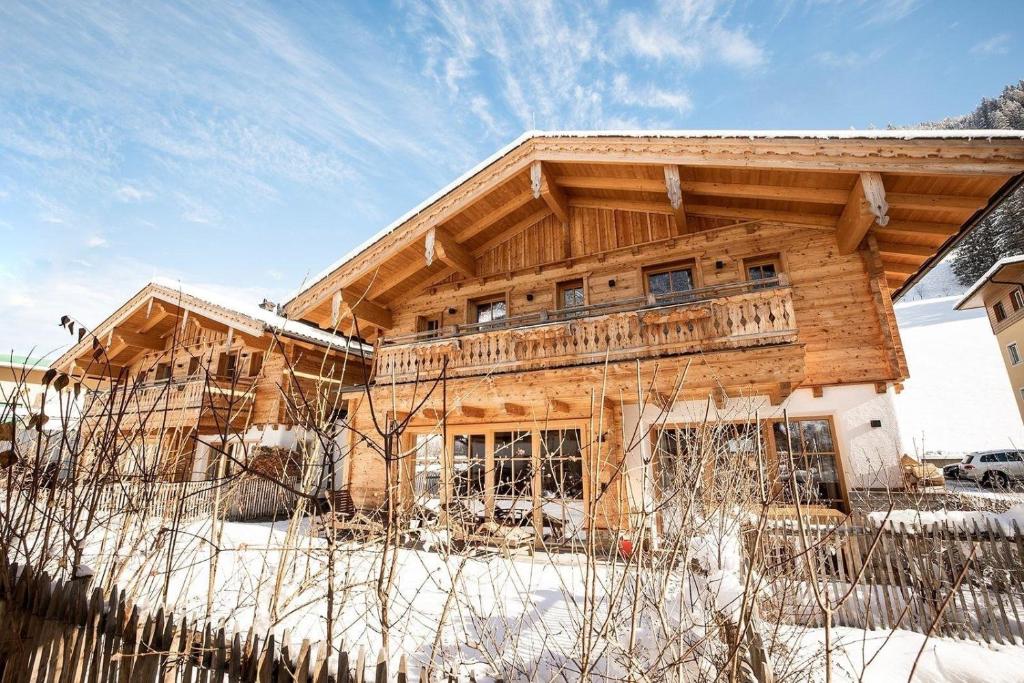 a wooden house in the snow with a fence at Birnbaum Chalet Kreuzkogel mit Naturbadesee und eingezäunten Garten in Grossarl