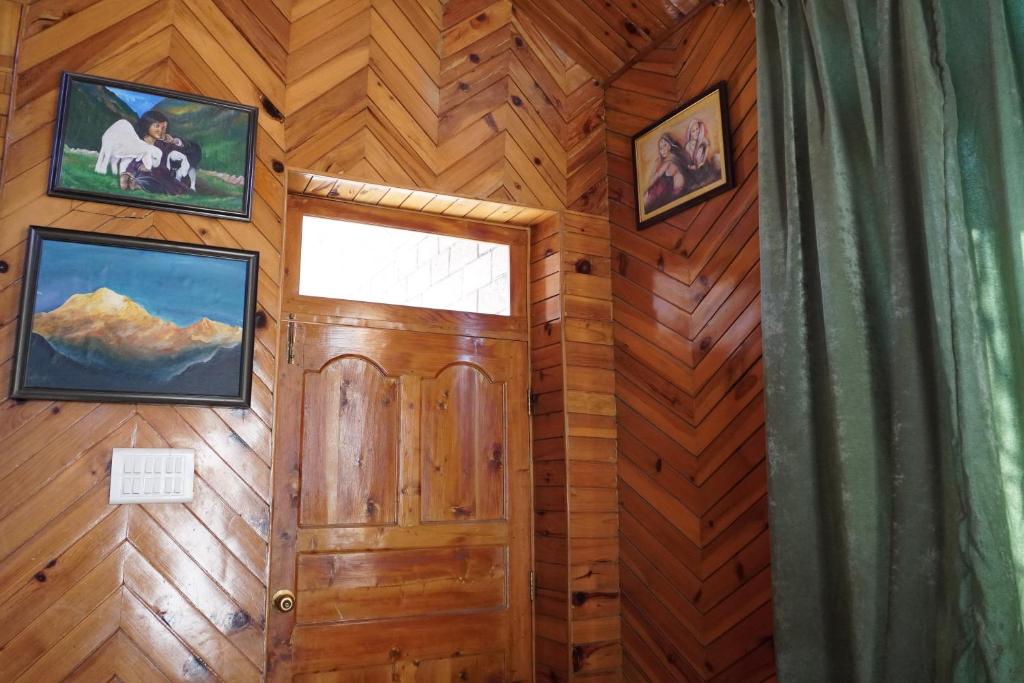 Habitación con pared de madera, puerta y ventana. en The Vintage Inn by suman cottage, en Manali
