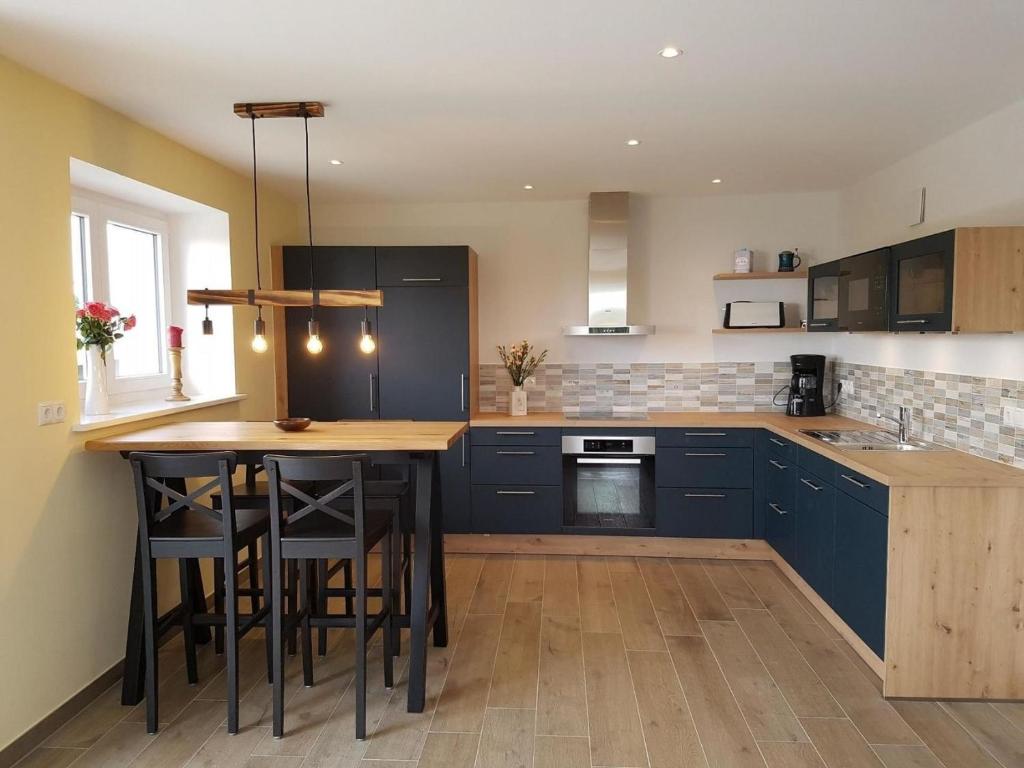 a kitchen with blue cabinets and a wooden table at Lindenstuuv in Mittelangeln
