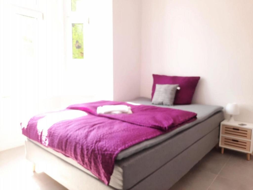 a bed with a purple blanket on it in a bedroom at Villa Mariensiel 1OG li in Sande