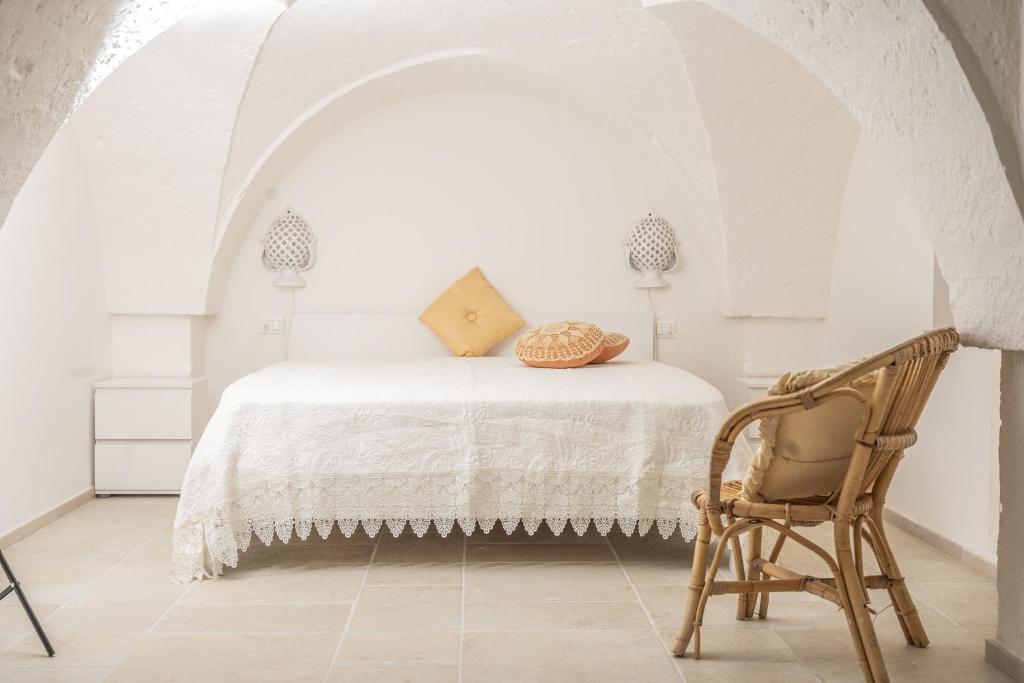 a white bedroom with a bed and a chair at Mille Lire - Family suites in Monopoli