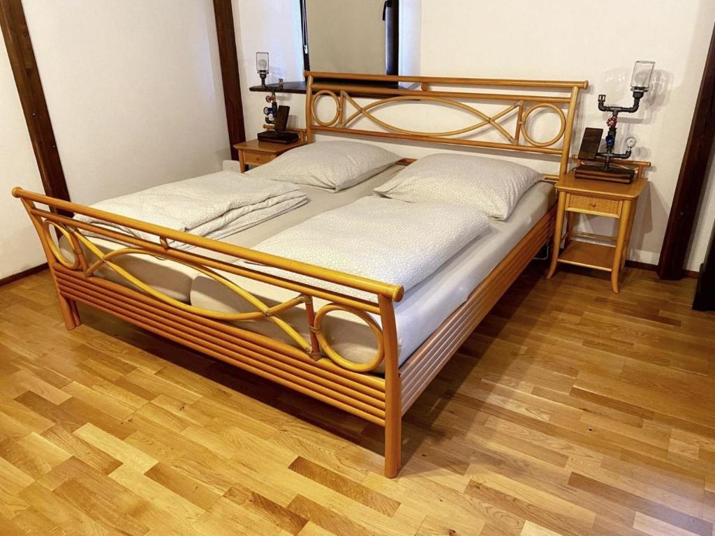 duże drewniane łóżko w pokoju z dwoma stołami w obiekcie Ferienwohnung Penzlin im Rittergut Leppersdorf w mieście Leppersdorf