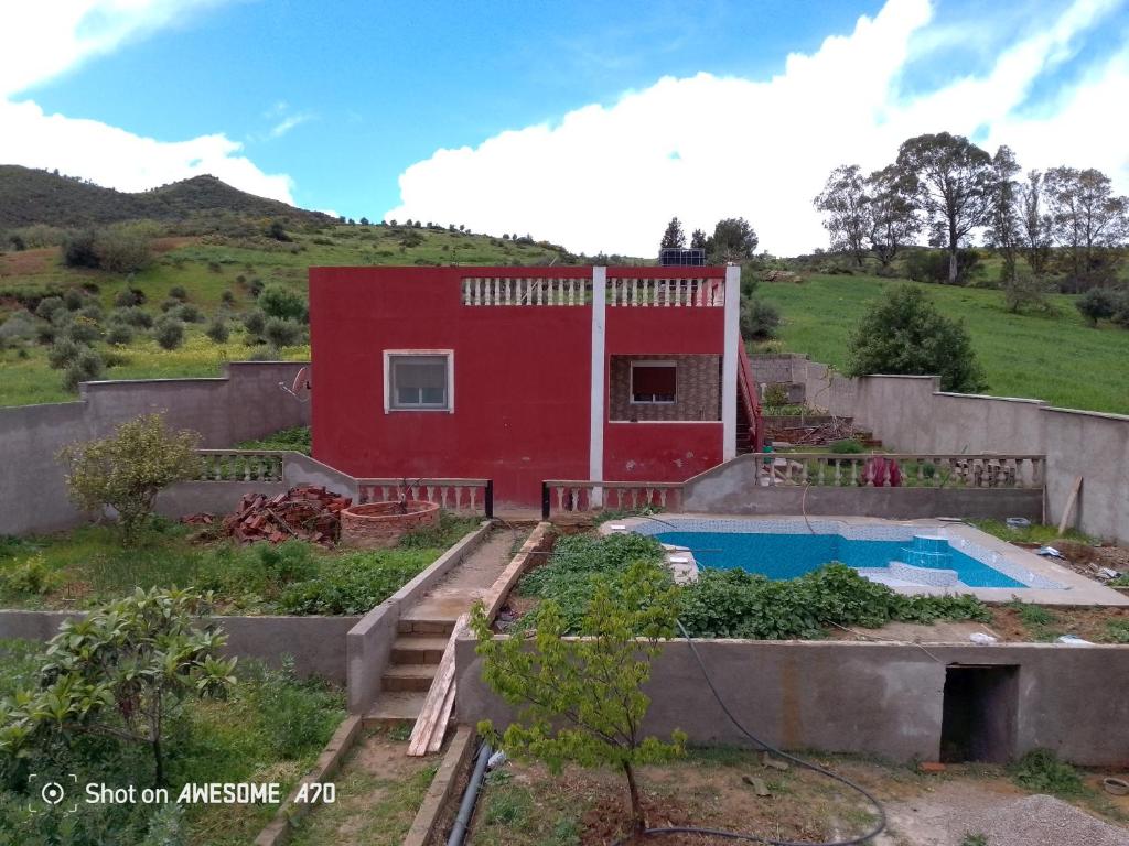 a red house with a swimming pool in front of it at دار الضيافه امال in Tétouan