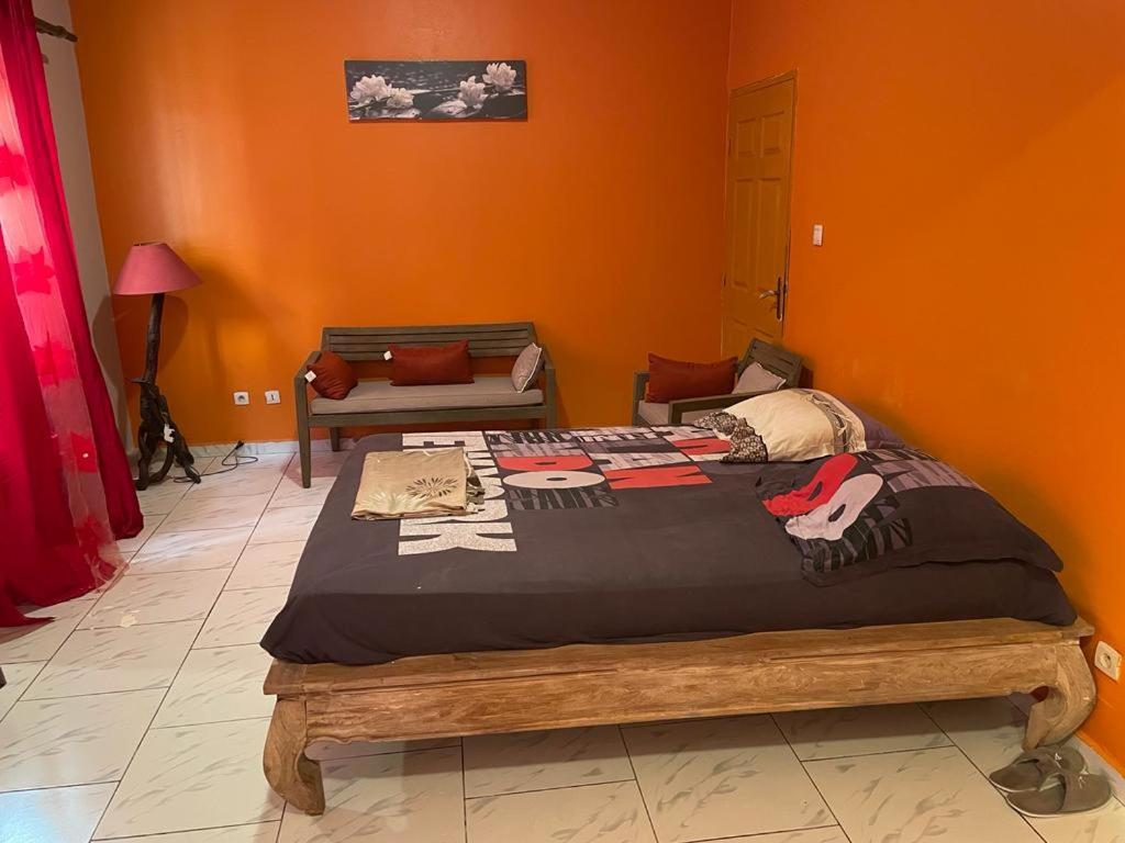 een groot bed in een kamer met een oranje muur bij Appartement T3 Bandrélé in Bandrélé