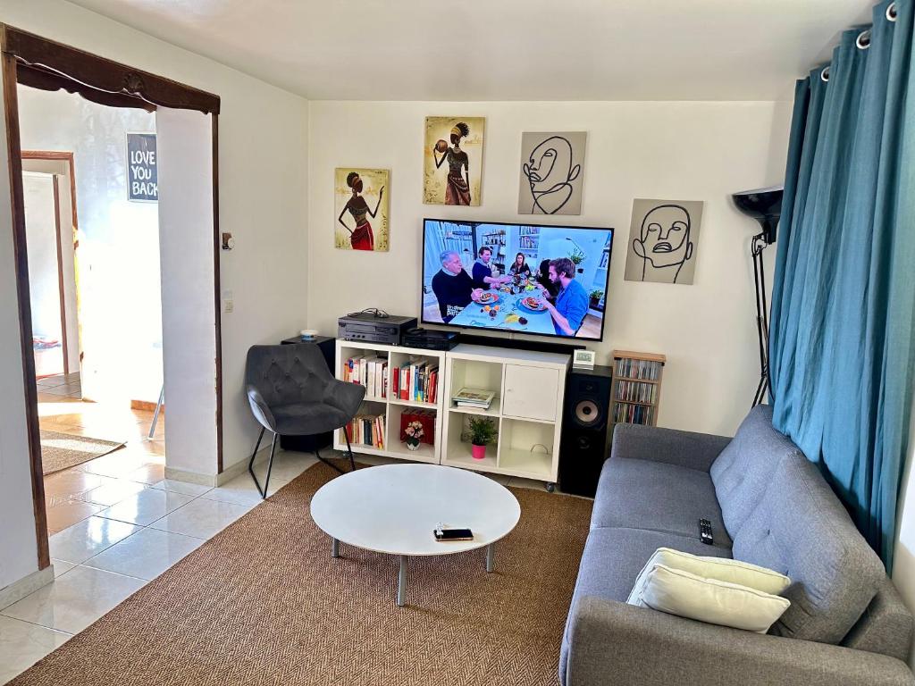 a living room with a couch and a tv at Aubervilliers maison de ville près métro 7 by immo kit bnb in Aubervilliers