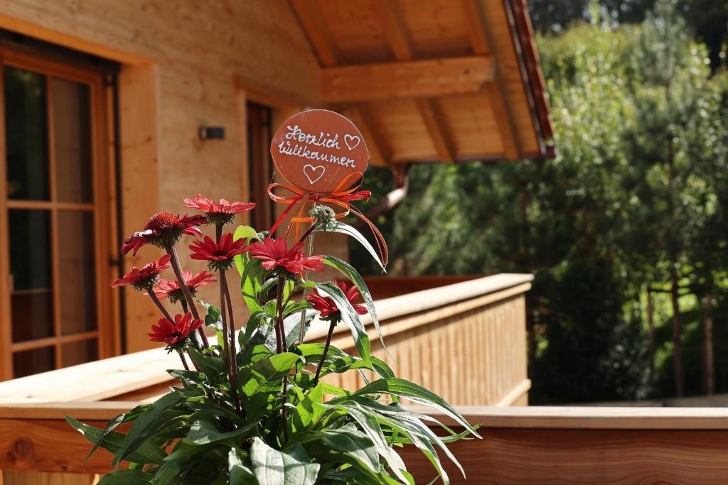 a vase with red flowers in front of a house at Chalet22 beim Flößerhaus Beuerberg in Eurasburg