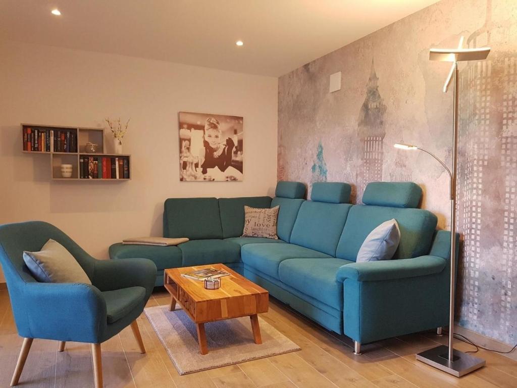a living room with a blue couch and two chairs at Melkkamer in Mittelangeln