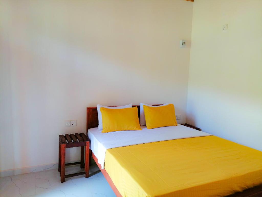 a bedroom with a bed with two yellow pillows at Sinharaja Cabana in Matara