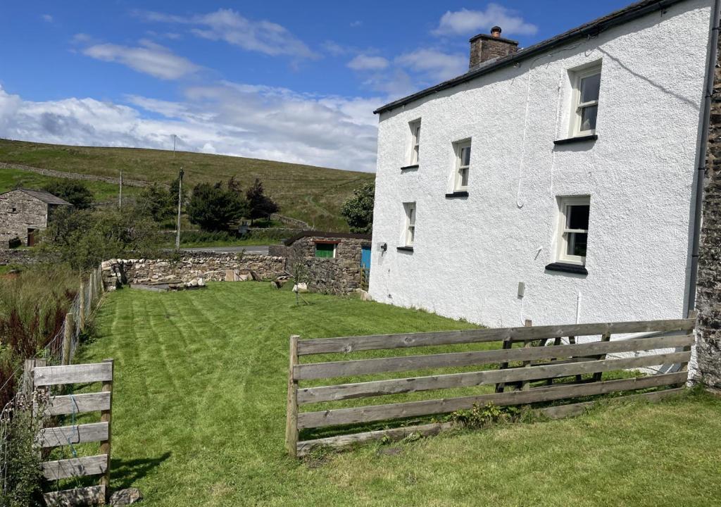 a white house with a wooden fence next to it at Moorland View in Cotterdale