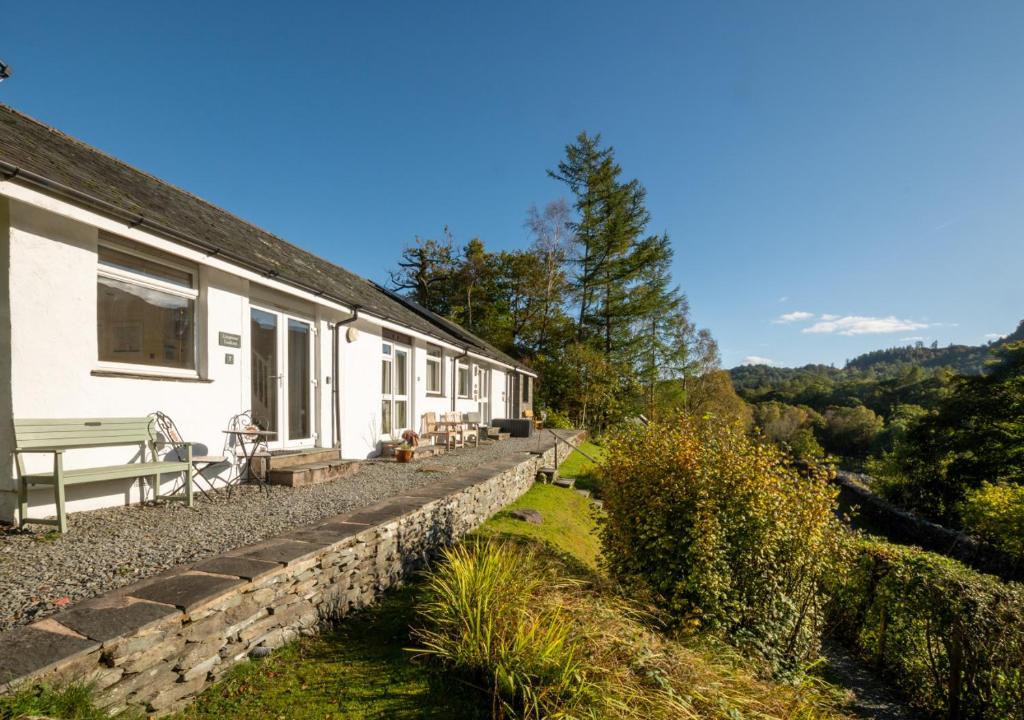 a white house with a stone wall and a bench at Lingmoor Lookout in Chapel Stile