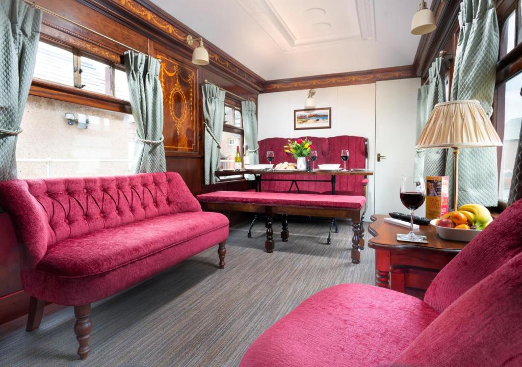 a living room with a red couch and a table at Irt Pullman Carriage in Ravenglass