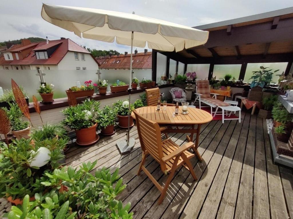 une terrasse en bois avec une table et un parasol dans l'établissement Ferienwohnung für 2 Personen 70 m in Eschwege, à Eschwege