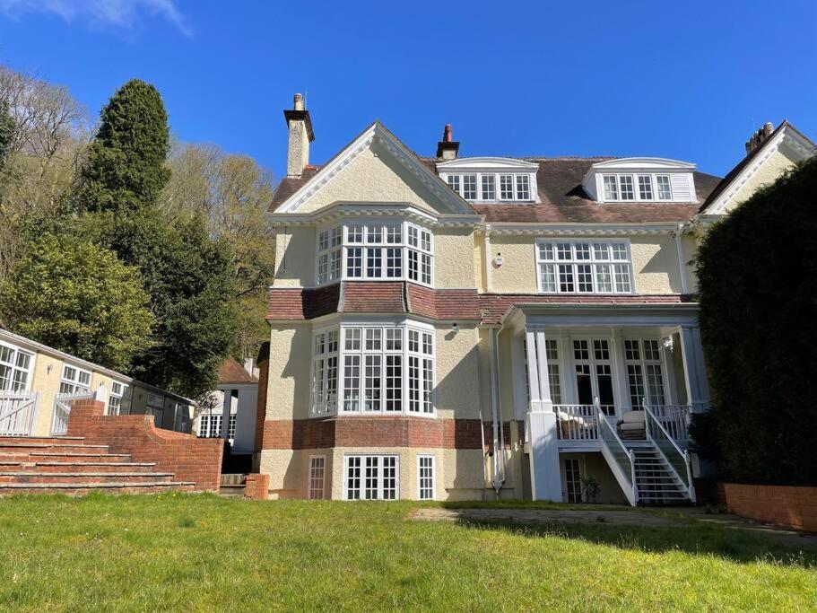 ein großes Haus mit weißen Fenstern auf einem grünen Rasen in der Unterkunft Idyllic Country House in Haslemere in Haslemere