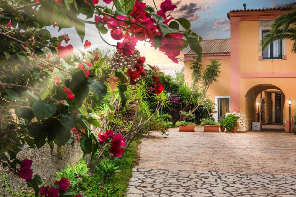 un patio de una casa con flores rojas en Casale Romano Resort e Relais, en Motta Camastra