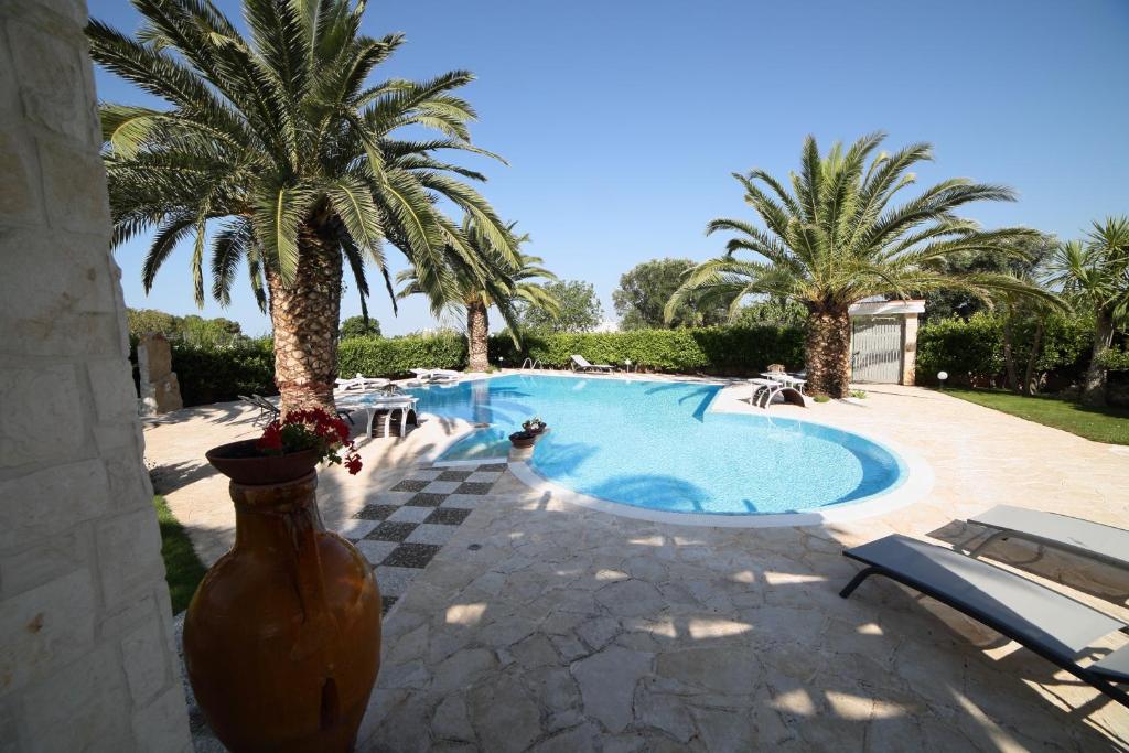 una gran piscina con palmeras en un patio en L'OASI DA ROSY, en Martina Franca