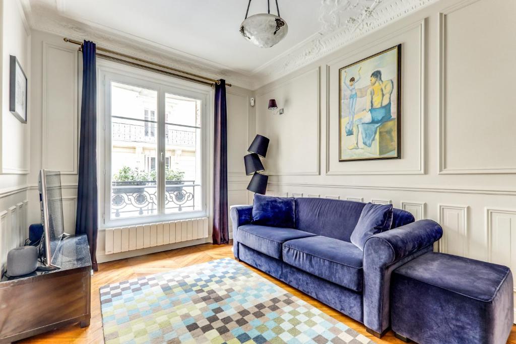 a living room with a blue couch and a window at Appartement charmant Quartier culturel in Paris