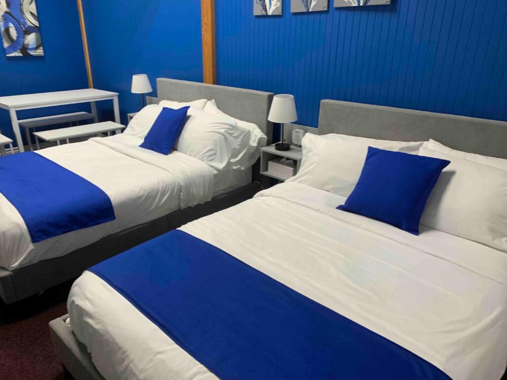 two beds in a hotel room with blue walls at Motel Magistral in St-Raphael-de-Bellechasse