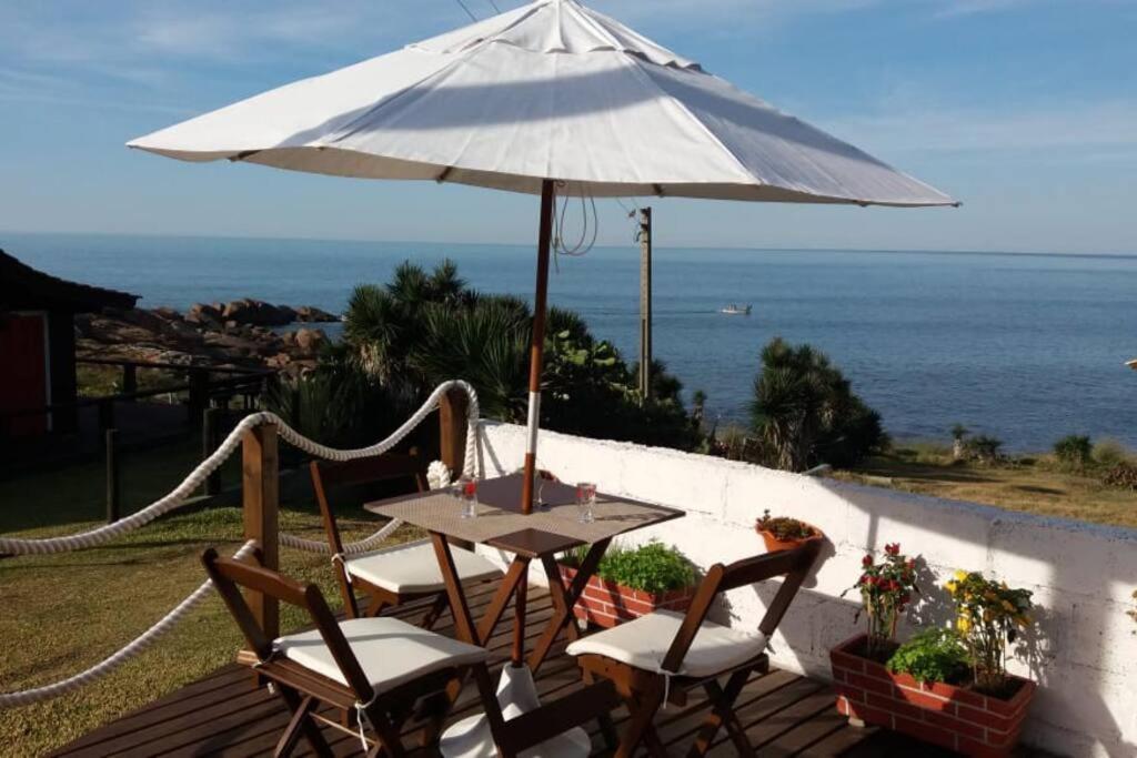 una mesa y sillas con una sombrilla en la cubierta en Toca da Garoupa, en Laguna