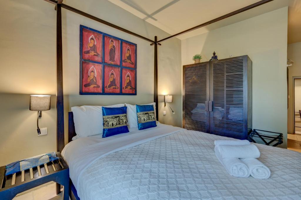a bedroom with a large white bed with blue pillows at Hostellerie Le Paradou in Lourmarin