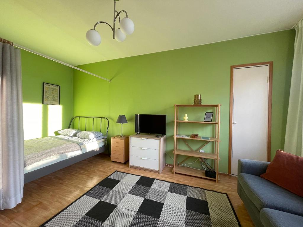 een slaapkamer met groene muren en een bed en een bank bij The Golden Glow Apartment Turku in Turku