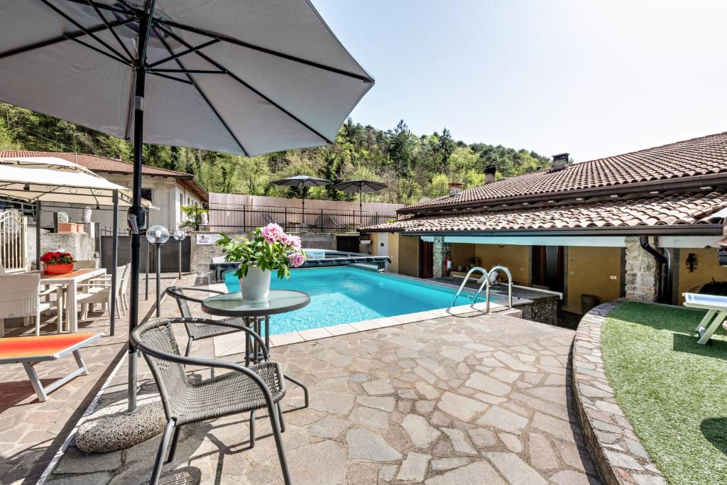un patio con mesa y sombrilla junto a la piscina en Residence Tatiana A1, en Tremosine Sul Garda