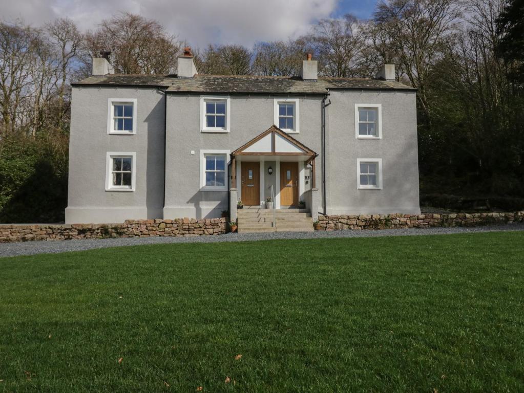 uma casa grande com um relvado em frente em Dalegarth Hall Farm Cottage 2 em Holmrook