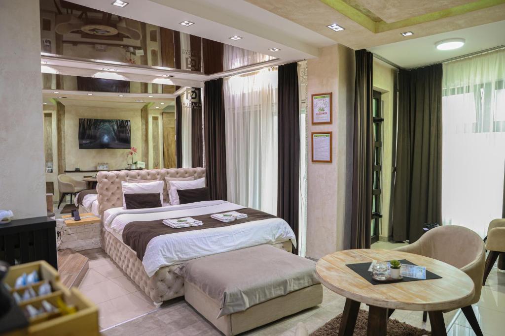 a bedroom with a large bed and a table at Design Apartment GRAND SPA LUX 4 STAR "MALIBU" Completely PRIVATE Wellness & Spa FREE INCLUDED Jacuzzi & Salt Wall & Fire place & 3D Ceilings & Business WiFi & NETFLIX & LED Lights & Keyless code entry & FULL SMART APP & SECURE 2 Parking place in Ćuprija