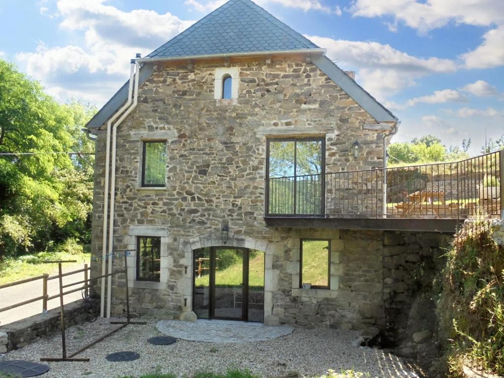 une maison en pierre avec un balcon au-dessus dans l'établissement Maison spacieuse à Castelnau-de-Mandailles avec cheminée 250 m², à Castelnau-de-Mandailles