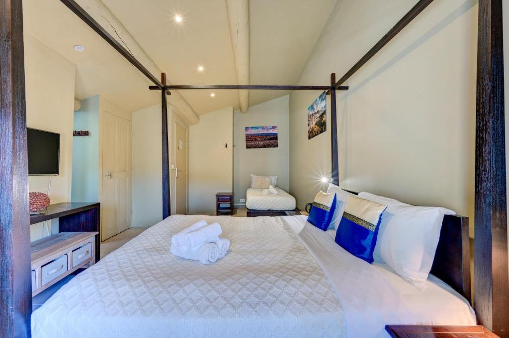 a bedroom with a large bed with blue and white pillows at Hostellerie Le Paradou in Lourmarin