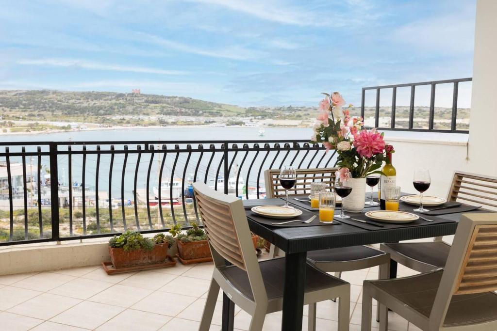 a table on a balcony with a view of the ocean at Ghadirabay Seafront With Sea Views By Homely in Mellieħa
