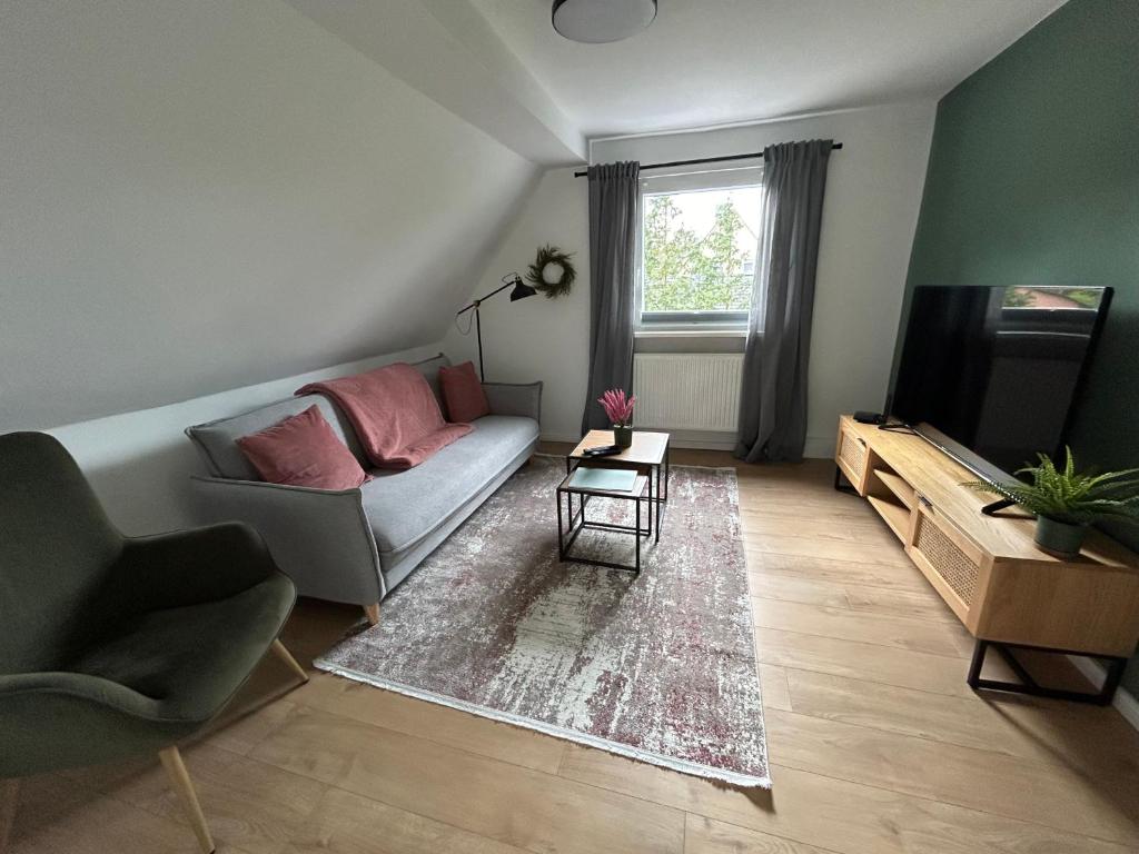 - un salon avec un canapé et une télévision dans l'établissement Ferienwohnung am Wald in der Südheide, à Unterlüß