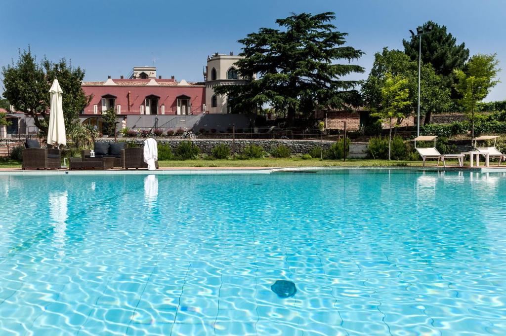 una gran piscina de agua azul con un edificio al fondo en Villa Eremo Sant'Emilia, en Trecastagni