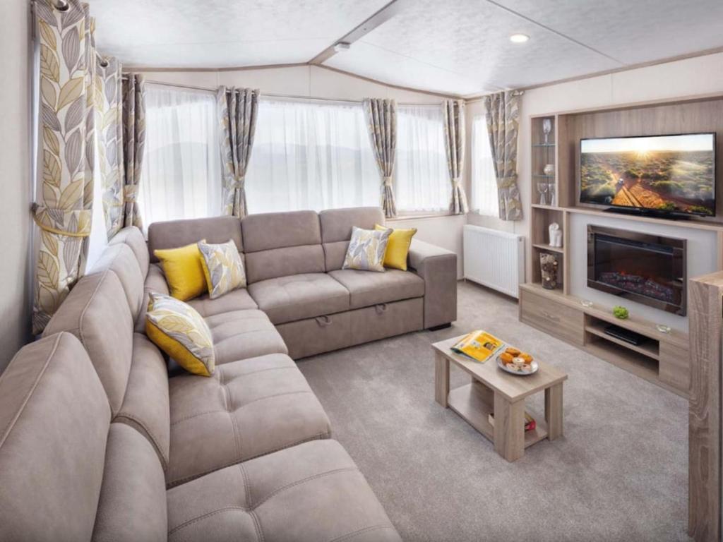 a living room with a couch and a television at SBL38 Caravan at Camber Sands - quiet location in Camber