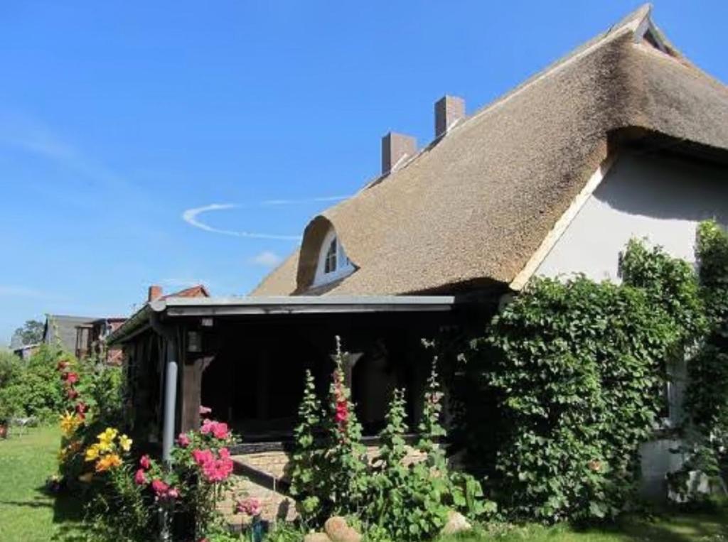 una casa con tetto di paglia e alcuni fiori di Koras Dachkammer a Ribnitz-Damgarten