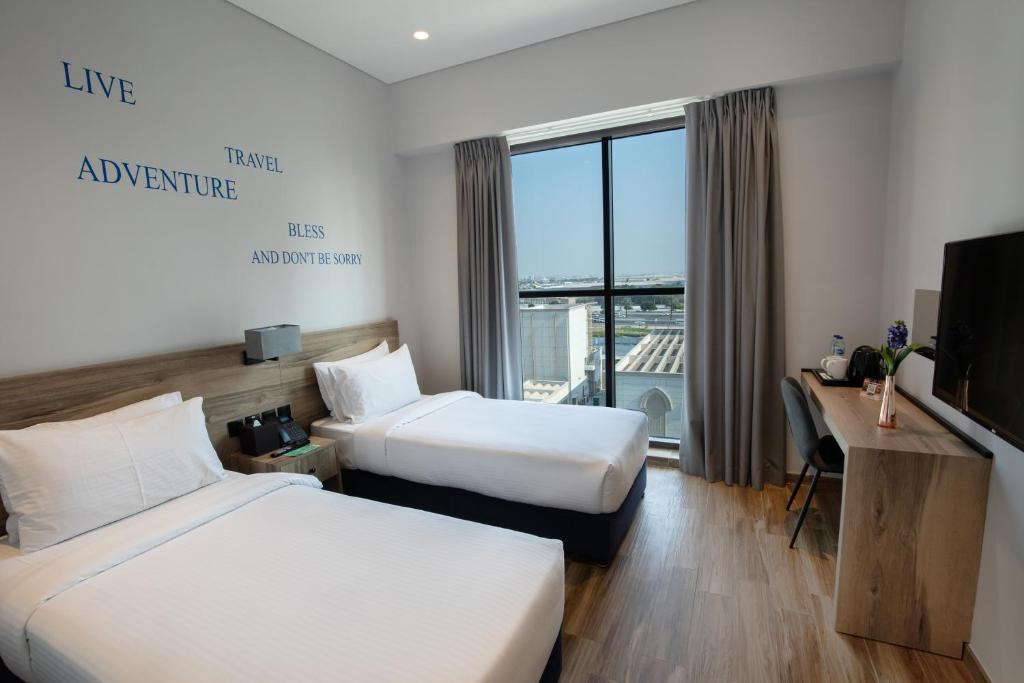 a hotel room with two beds and a television at Kingsgate Canal Hotel by Millennium in Dubai