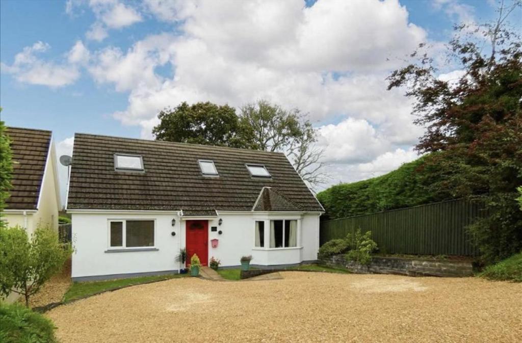 a white house with a red door and a fence at Beautiful 4-Bed House with countryside views in Haverfordwest